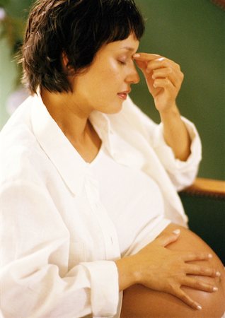 Pregnant woman with hand on stomach, touching bridge of nose Stock Photo - Premium Royalty-Free, Code: 632-01140092