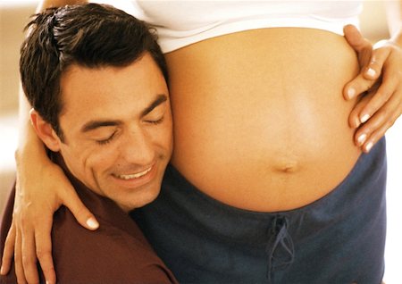 simsearch:632-01140106,k - Man pressing cheek to pregnant woman's stomach, close-up Stock Photo - Premium Royalty-Free, Code: 632-01140104