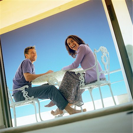 summer holiday frame - Man and woman sitting at table outdoors, smiling, seen through window, low angle view Stock Photo - Premium Royalty-Free, Code: 632-01142674