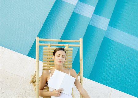 picture of lady on sleeping lounge chair - Woman sleeping in lounge chair at edge of pool with book on chest Stock Photo - Premium Royalty-Free, Code: 632-01154201