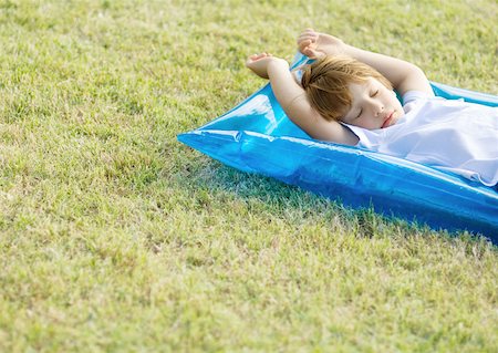 Petit garçon endormi sur un radeau pneumatique, sur l'herbe Photographie de stock - Premium Libres de Droits, Code: 632-01154962