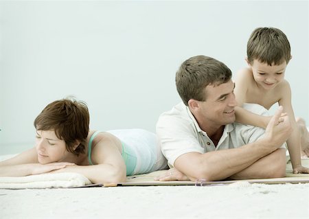 Family lying on beach, man and son thumb wrestling while mother sleeps Stock Photo - Premium Royalty-Free, Code: 632-01155325