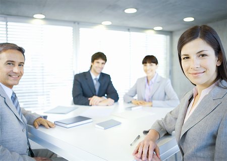 simsearch:632-01155400,k - Executives sitting around table, smiling at camera Stock Photo - Premium Royalty-Free, Code: 632-01155381