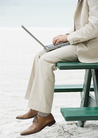 Businessman sitting on picnic table on beach, using laptop, chest down Stock Photo - Premium Royalty-Free, Code: 632-01155551