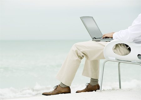 Businessman sitting in chair, using laptop on beach, waist down Stock Photo - Premium Royalty-Free, Code: 632-01155578