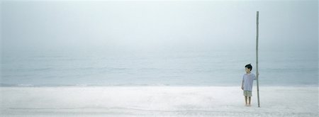 Boy standing on beach, holding big stick Stock Photo - Premium Royalty-Free, Code: 632-01156103