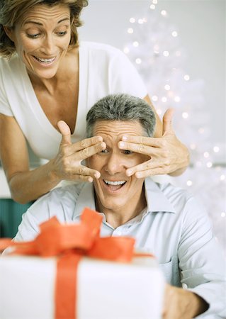 Woman surprising husband with christmas present Stock Photo - Premium Royalty-Free, Code: 632-01156342
