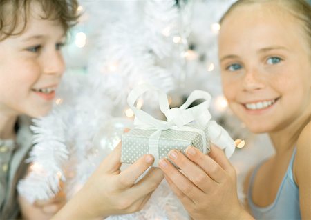 simsearch:632-06354083,k - Boy handing sister gift in front of christmas tree Fotografie stock - Premium Royalty-Free, Codice: 632-01156376