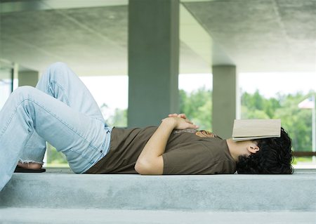 pereza - Male college student lying on ground with book covering face Foto de stock - Sin royalties Premium, Código: 632-01156829