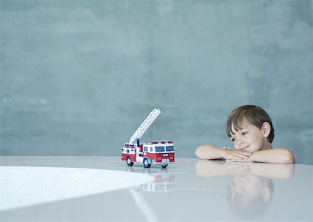 Boy looking longingly at toy firetruck Stock Photo - Premium Royalty-Free, Code: 632-01156886