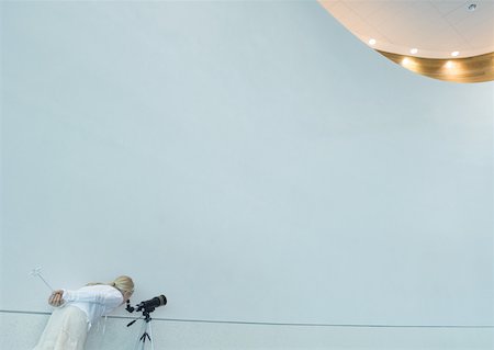 Girl looking through telescope, holding magic wand behind back Stock Photo - Premium Royalty-Free, Code: 632-01156895