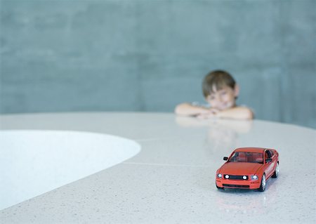 Boy looking longingly at toy sports car Stock Photo - Premium Royalty-Free, Code: 632-01156919