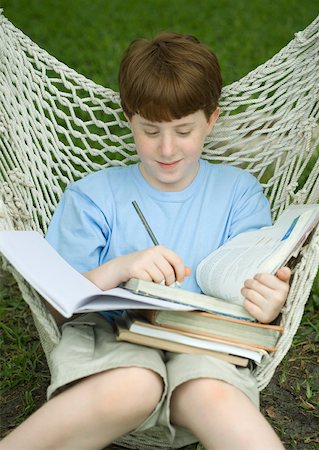 simsearch:632-03403124,k - Boy sitting in hammock doing homework Foto de stock - Royalty Free Premium, Número: 632-01157063