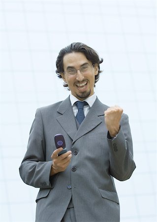 Businessman holding cell phone, making fist and shouting Stock Photo - Premium Royalty-Free, Code: 632-01157424