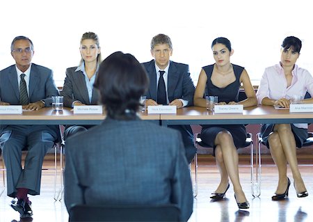 reducción de personal - Executives sitting at conference table, looking at man in foreground Foto de stock - Sin royalties Premium, Código: 632-01157551