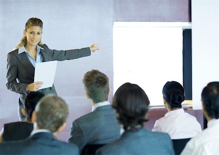 simsearch:632-01157586,k - Executives sitting in seminar, woman standing facing group, gesturing to screen Stock Photo - Premium Royalty-Free, Code: 632-01157562