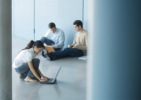 Young woman and two young men using laptops on floor Stock Photo - Premium Royalty-Free, Code: 632-01157704