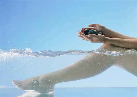 Woman's legs in water and hands holding stones Stock Photo - Premium Royalty-Free, Code: 632-01158680