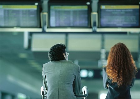 Businessman and businesswoman sitting under airport departure and arrival monitors, rear view Foto de stock - Sin royalties Premium, Código: 632-01150099