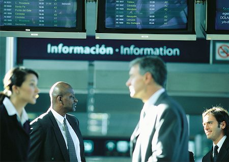 simsearch:695-03388701,k - Businesspeople talking in front of an airport information sign. Stock Photo - Premium Royalty-Free, Code: 632-01150101