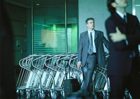 simsearch:695-03388701,k - Businessmen standing in front of airport luggage carts. Stock Photo - Premium Royalty-Free, Code: 632-01150103
