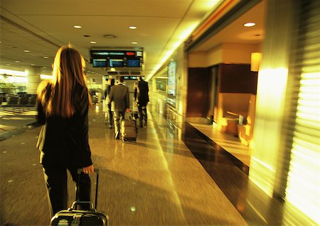 simsearch:632-05554045,k - Businesswoman pulling suitcase through airport terminal. Foto de stock - Sin royalties Premium, Código: 632-01150124