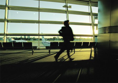 simsearch:400-03915225,k - Silhouette of businessperson hurrying through airport terminal. Foto de stock - Royalty Free Premium, Número: 632-01150130