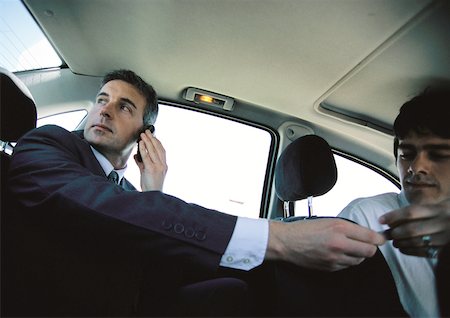 Businessman on cell phone in backseat of car paying taxi driver, low angle view Foto de stock - Sin royalties Premium, Código: 632-01150133