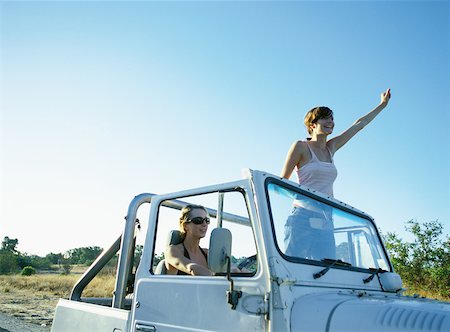 Two women in 4x4 vehicle, one standing up, waving Foto de stock - Sin royalties Premium, Código: 632-01150295