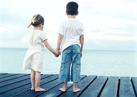 Boy and girl standing on dock holding hands, rear view Stock Photo - Premium Royalty-Free, Code: 632-01150339