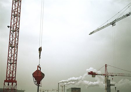 factory pollution - Cranes and factory smoke stacks, low angle view Stock Photo - Premium Royalty-Free, Code: 632-01150437