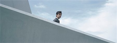 Man standing behind concrete wall, low angle view Stock Photo - Premium Royalty-Free, Code: 632-01151404