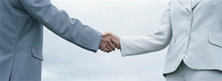 Woman and man in suits shaking hands, mid-section with sky in background Stock Photo - Premium Royalty-Free, Code: 632-01151417