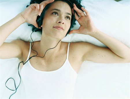 simsearch:632-01151438,k - Woman lying on back on bed with earphones on and hands at side of head Foto de stock - Sin royalties Premium, Código: 632-01151455