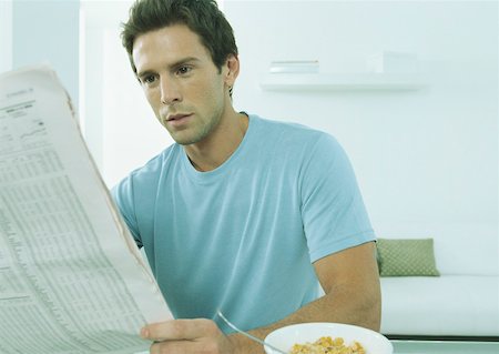 simsearch:632-01148045,k - Young man sitting at table with bowl of cereal holding financial page of newspaper Stock Photo - Premium Royalty-Free, Code: 632-01151503