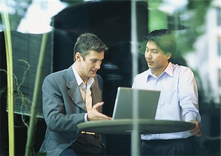 sales associate talking with customer - Businessmen sitting at cafe table, talking over laptop Stock Photo - Premium Royalty-Free, Code: 632-01152618