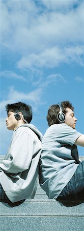 Two young men wearing headphones, sitting back to back Stock Photo - Premium Royalty-Free, Code: 632-01152727