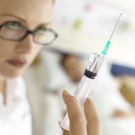 female nurse treating a patient - Nurse holding up syringe in front of patient Stock Photo - Premium Royalty-Free, Code: 632-01152759