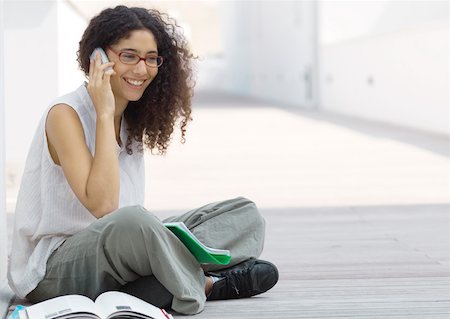 Young woman sitting indian style on ground, talking on cell phone Stock Photo - Premium Royalty-Free, Code: 632-01153551
