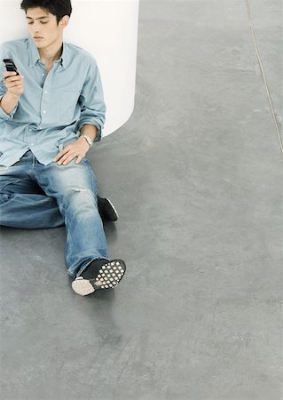 simsearch:632-01271195,k - Young man sitting on floor looking at cell phone Fotografie stock - Premium Royalty-Free, Codice: 632-01153582