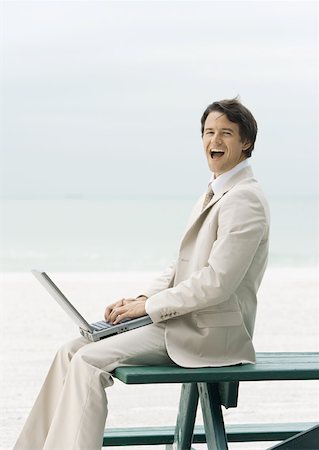 Businessman sitting on edge of picnic table at beach, using laptop Stock Photo - Premium Royalty-Free, Code: 632-01160290