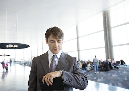 simsearch:632-01160695,k - Businessman checking watch in airport Stock Photo - Premium Royalty-Free, Code: 632-01160327