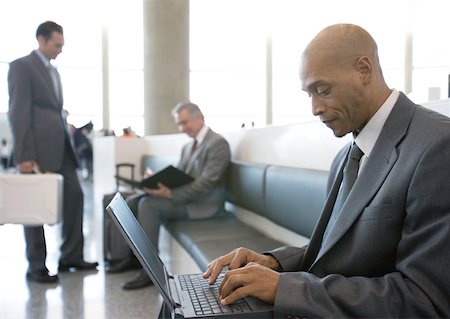 Businessman using laptop in airport lounge area Stock Photo - Premium Royalty-Free, Code: 632-01160321