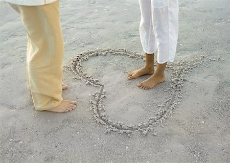 Woman standing inside heart drawn on beach, facing man, low section Stock Photo - Premium Royalty-Free, Code: 632-01161063