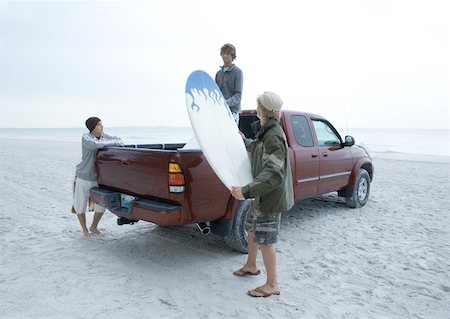 pick up truck and man - Three surfers taking surfboard out of back of pick-up truck, on beach Stock Photo - Premium Royalty-Free, Code: 632-01161503