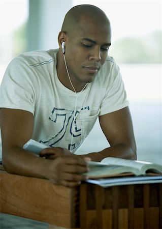 Male student studying and listening to earphones Stock Photo - Premium Royalty-Free, Code: 632-01161704