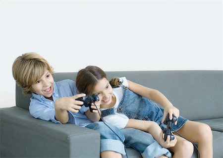 Enfants assis sur le canapé, tenant les manettes de jeu Photographie de stock - Premium Libres de Droits, Code: 632-01194045