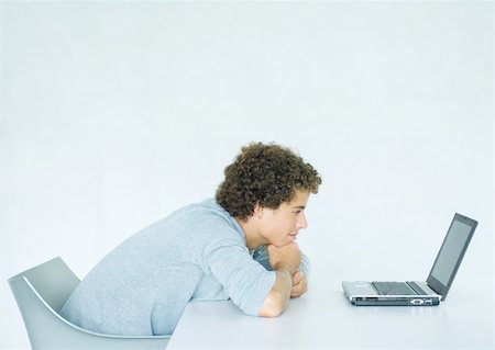 slumped over - Young man sitting, leaning on desk, facing laptop computer Stock Photo - Premium Royalty-Free, Code: 632-01194040