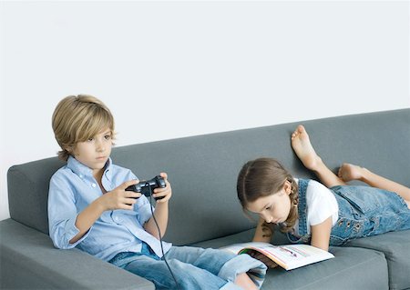 simsearch:632-01148441,k - Junge sitzt auf dem Sofa, Betriebs-Joystick, Mädchen neben ihm Lesen Stockbilder - Premium RF Lizenzfrei, Bildnummer: 632-01194085