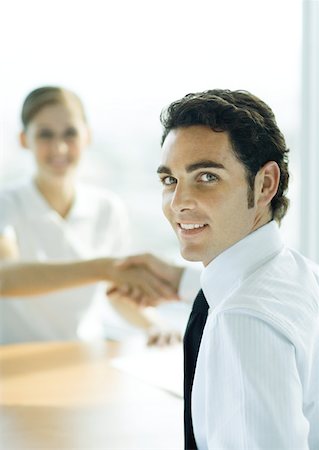 Man and woman shaking hands across table, man smiling over shoulder at camera Foto de stock - Sin royalties Premium, Código: 632-01194121